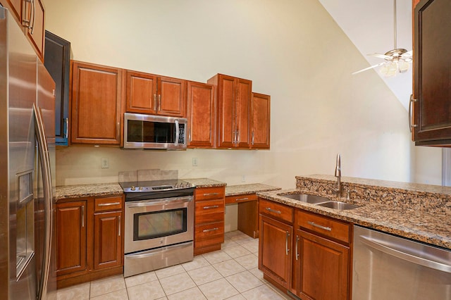 kitchen featuring light tile patterned floors, light stone counters, a sink, a ceiling fan, and appliances with stainless steel finishes