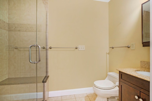 full bathroom with tile patterned flooring, toilet, vanity, baseboards, and a tile shower