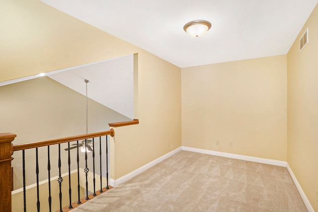 empty room with visible vents, baseboards, and light colored carpet