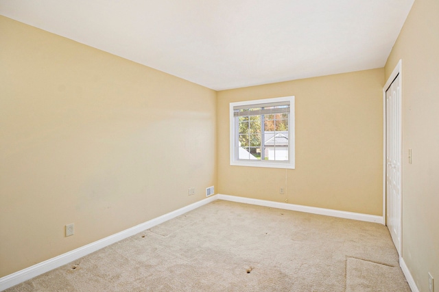 unfurnished bedroom featuring baseboards, a closet, visible vents, and light colored carpet