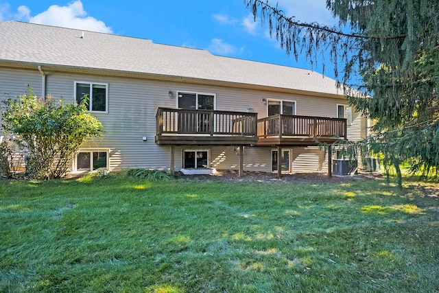 rear view of house featuring central AC, a yard, a wooden deck, and roof with shingles