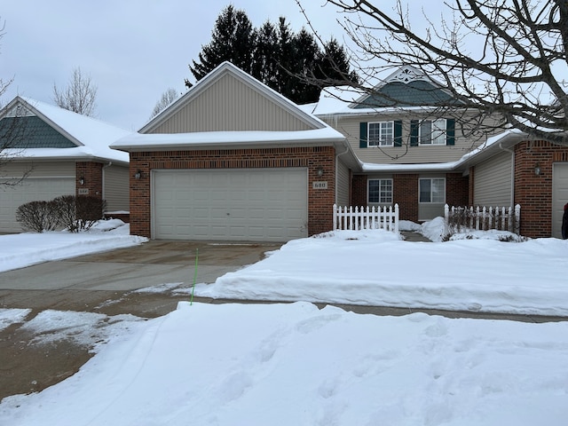 view of front of house featuring an attached garage, driveway, fence, and brick siding