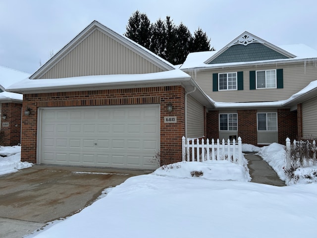 view of front of home with brick siding, an attached garage, and fence