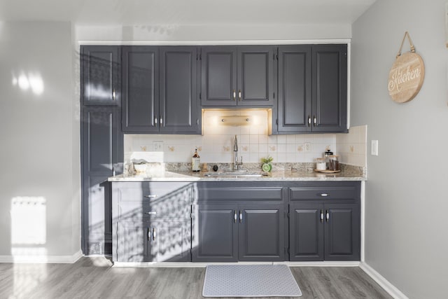 bar featuring radiator, sink, light stone counters, dark hardwood / wood-style floors, and decorative backsplash