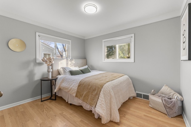 bedroom with light wood-type flooring and crown molding