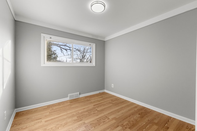 empty room with crown molding and light hardwood / wood-style flooring