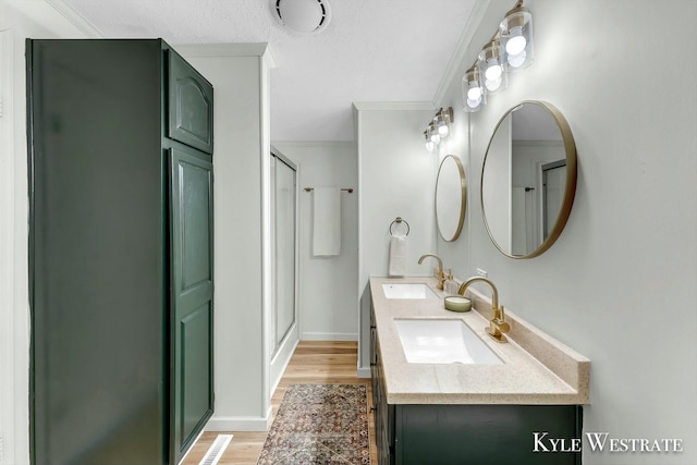 bathroom featuring hardwood / wood-style flooring, vanity, ornamental molding, and walk in shower