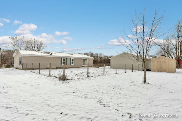 snow covered rear of property with a storage shed