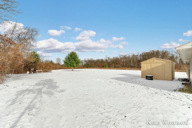 snowy yard featuring a storage shed