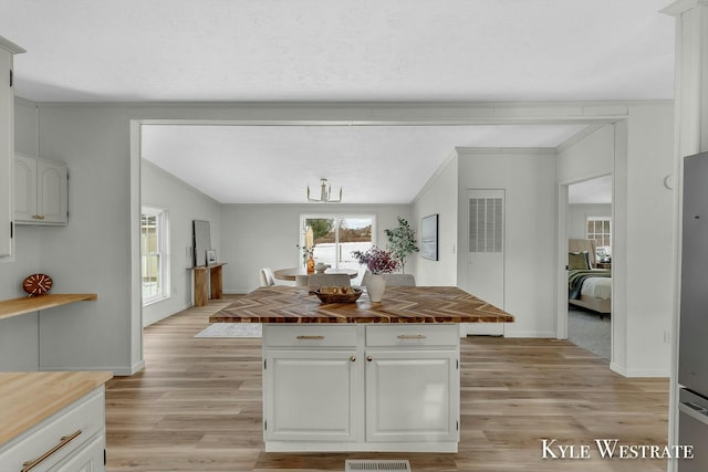 kitchen featuring a center island, white cabinets, light wood-type flooring, and wood counters