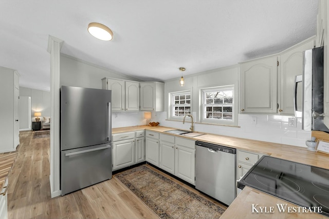 kitchen featuring white cabinetry, sink, backsplash, appliances with stainless steel finishes, and light wood-type flooring