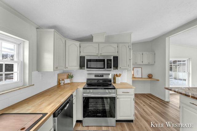 kitchen featuring wood counters, appliances with stainless steel finishes, backsplash, white cabinetry, and lofted ceiling