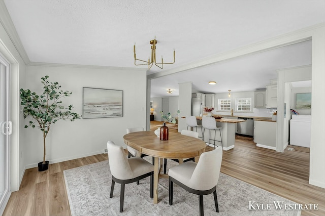 dining area with light hardwood / wood-style flooring, an inviting chandelier, and ornamental molding