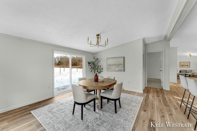 dining area featuring a textured ceiling, light hardwood / wood-style flooring, an inviting chandelier, and crown molding