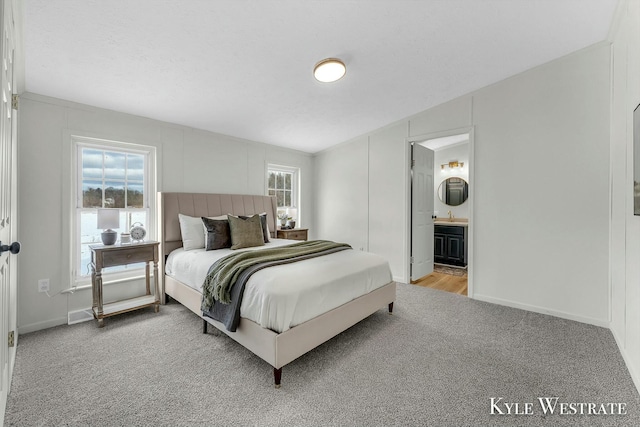 carpeted bedroom featuring connected bathroom and sink