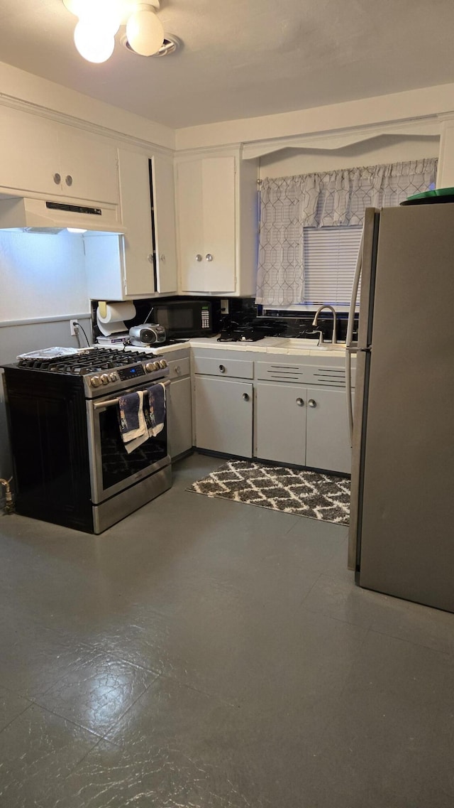 kitchen with stainless steel range with gas cooktop, decorative backsplash, freestanding refrigerator, white cabinets, and under cabinet range hood