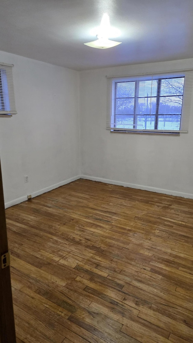 unfurnished room featuring baseboards and dark wood finished floors