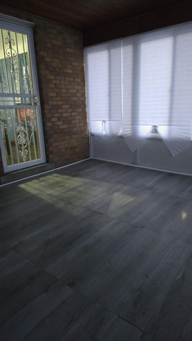 spare room featuring brick wall and wood finished floors