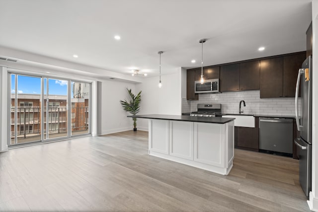 kitchen with a center island, tasteful backsplash, pendant lighting, appliances with stainless steel finishes, and light wood-type flooring