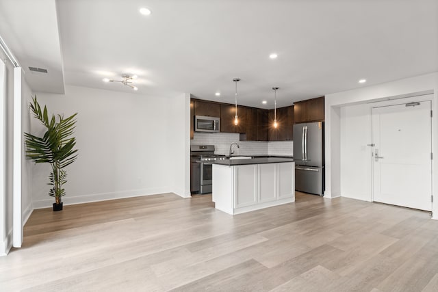 kitchen featuring appliances with stainless steel finishes, dark brown cabinetry, sink, a center island, and hanging light fixtures