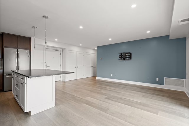 kitchen with hanging light fixtures, stainless steel fridge, light wood-type flooring, a kitchen island, and dark brown cabinetry