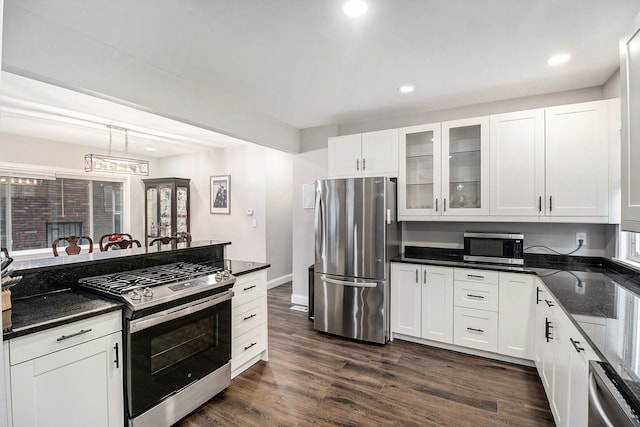 kitchen with pendant lighting, dark stone countertops, white cabinetry, and stainless steel appliances