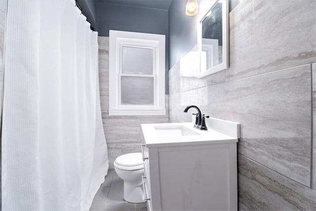 bathroom featuring tile patterned floors, vanity, tile walls, and toilet