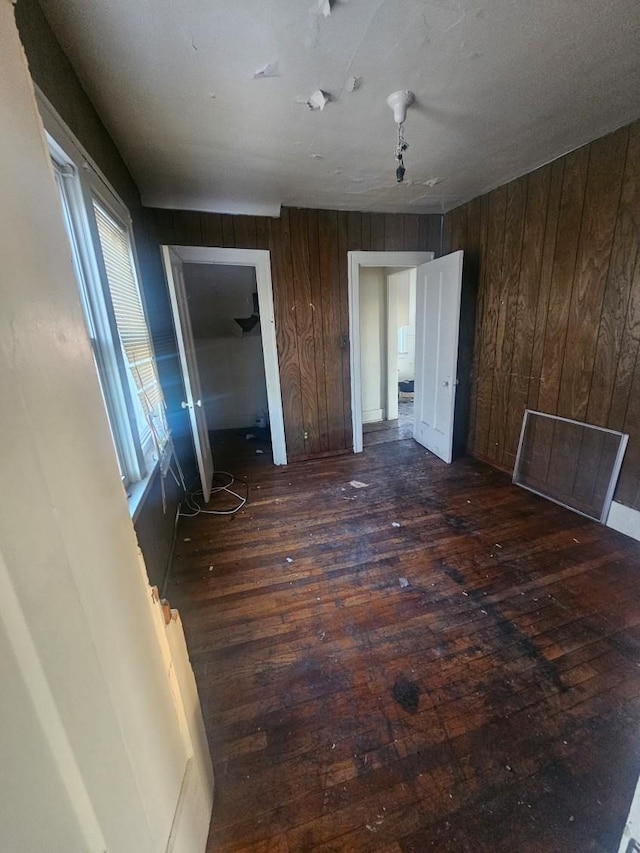 unfurnished bedroom featuring wood walls and dark hardwood / wood-style floors