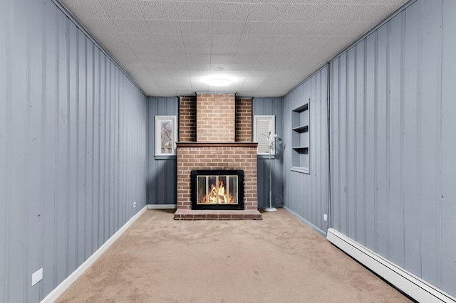 unfurnished living room featuring built in shelves, a fireplace, carpet floors, and a baseboard heating unit