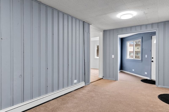 carpeted spare room with a baseboard heating unit