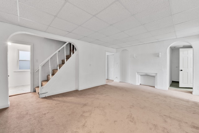 unfurnished living room with carpet flooring and a drop ceiling