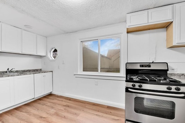 kitchen with a textured ceiling, sink, white cabinets, stainless steel gas stove, and light hardwood / wood-style floors