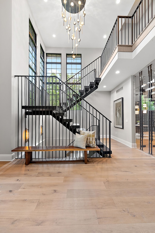 stairway with hardwood / wood-style floors and a notable chandelier