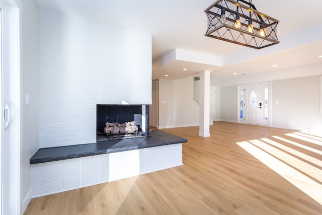 unfurnished living room featuring a multi sided fireplace and light hardwood / wood-style flooring