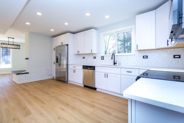 kitchen featuring tasteful backsplash, stainless steel appliances, sink, light hardwood / wood-style flooring, and white cabinetry