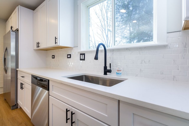 kitchen featuring appliances with stainless steel finishes, light hardwood / wood-style floors, white cabinetry, and sink