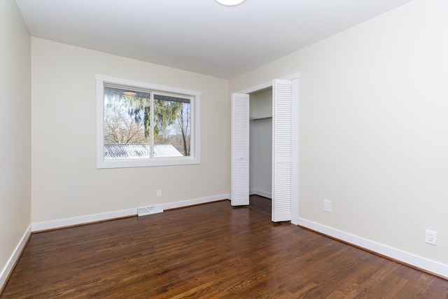 unfurnished bedroom with a closet and dark hardwood / wood-style flooring