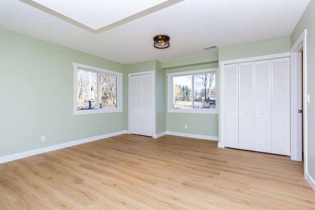 unfurnished bedroom featuring light hardwood / wood-style floors and multiple closets