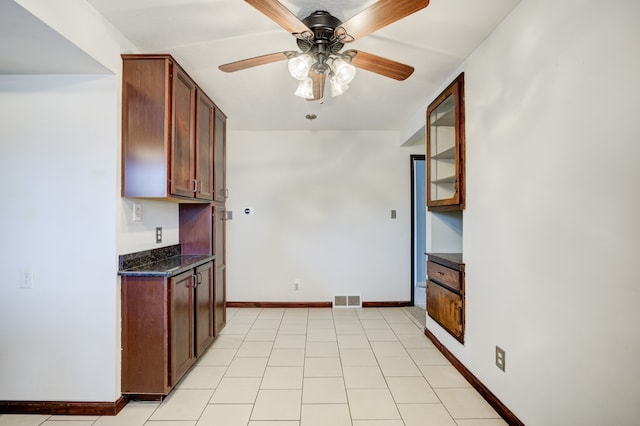 kitchen featuring ceiling fan and dark stone countertops