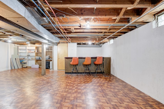 basement with dark parquet flooring and bar