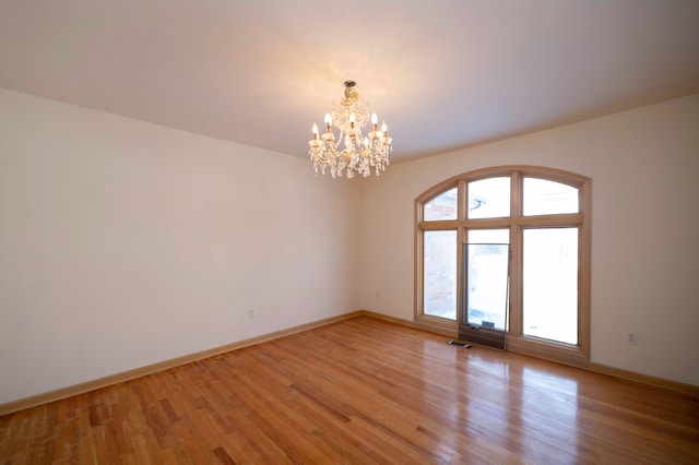 unfurnished room featuring a chandelier and light hardwood / wood-style flooring