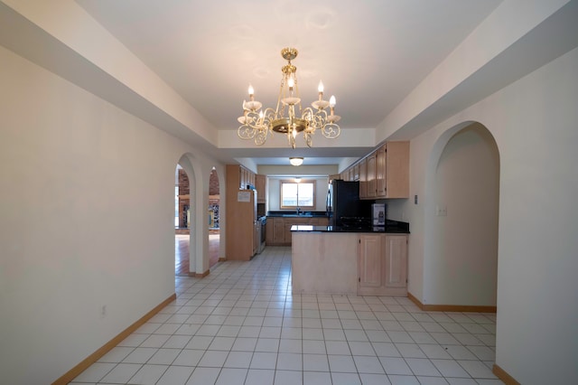 kitchen featuring light tile patterned flooring, black refrigerator, decorative light fixtures, a notable chandelier, and a raised ceiling