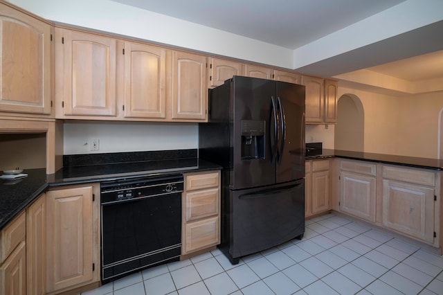 kitchen with light brown cabinetry, light tile patterned floors, black appliances, and dark stone countertops