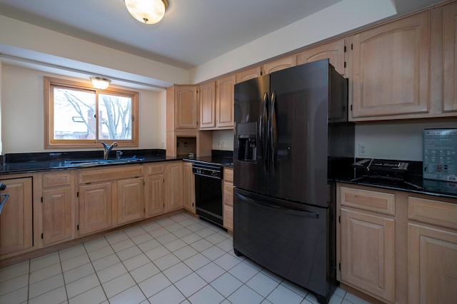 kitchen with light brown cabinetry, sink, black appliances, and dark stone counters