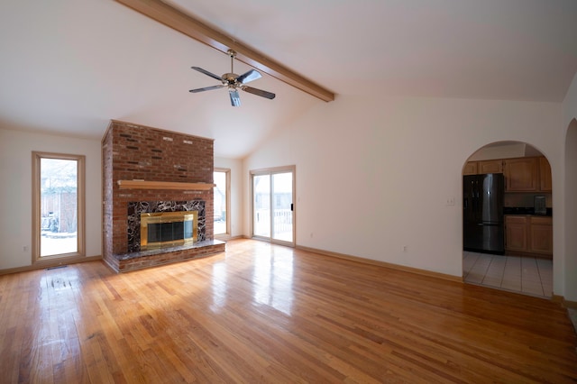 unfurnished living room with light hardwood / wood-style flooring, ceiling fan, beam ceiling, high vaulted ceiling, and a fireplace