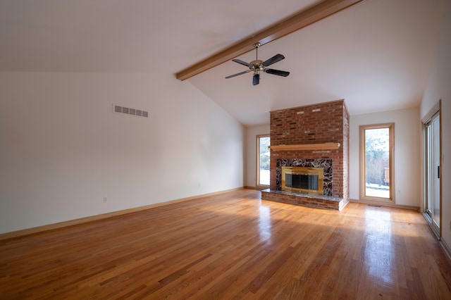 unfurnished living room featuring lofted ceiling with beams, ceiling fan, a brick fireplace, and light hardwood / wood-style floors