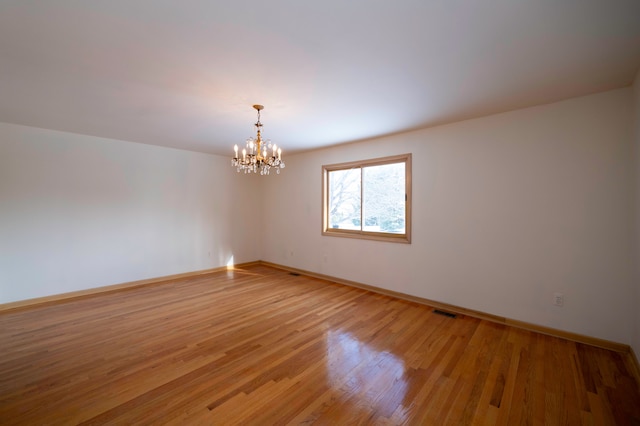 unfurnished room featuring wood-type flooring and a chandelier