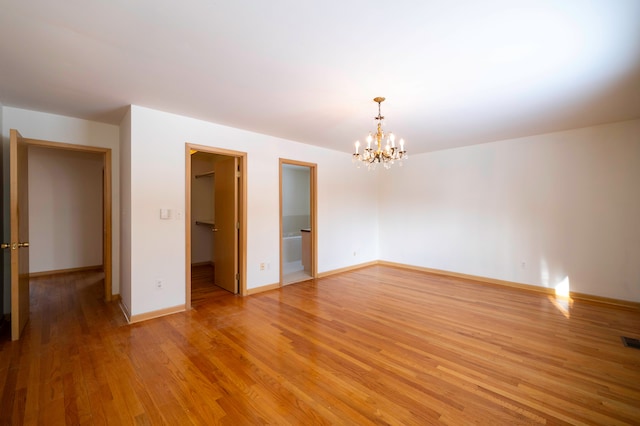 empty room with light hardwood / wood-style floors and a chandelier