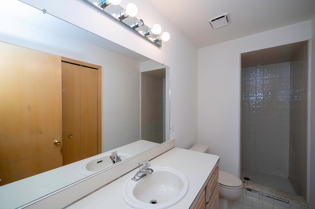 bathroom with tiled shower, vanity, and toilet