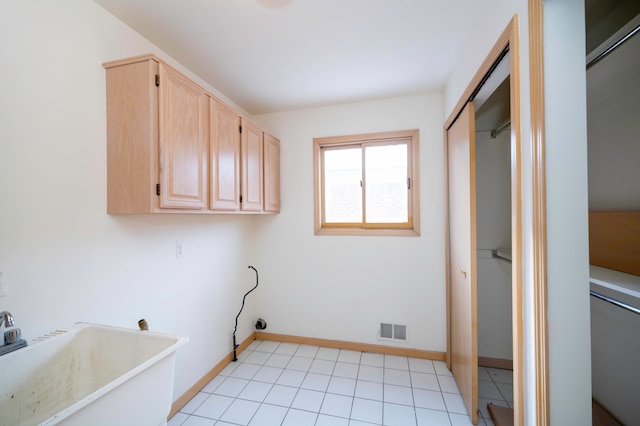 clothes washing area featuring cabinets and light tile patterned flooring